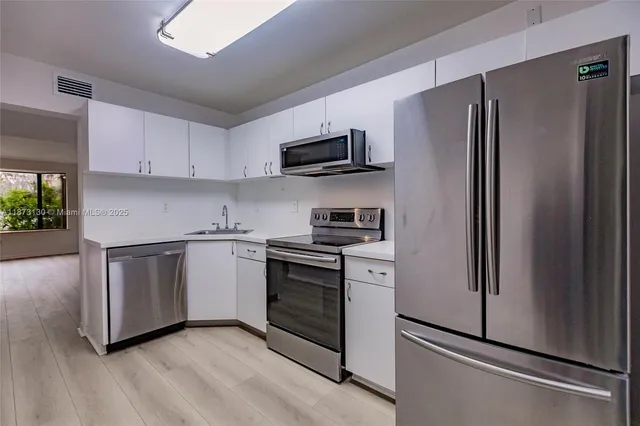 a kitchen with stainless steel appliances a refrigerator sink and microwave