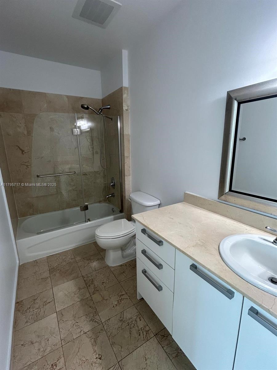 2525 Southwest 3rd Avenue, Unit 1402 Miami, FL 33129 - Photo 21 of 37 a bathroom with a granite countertop sink a toilet a mirror and shower