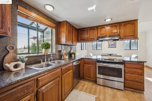 a kitchen with stainless steel appliances granite countertop a sink stove and cabinets