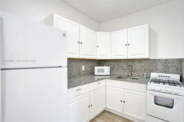 a kitchen with granite countertop white cabinets and white appliances