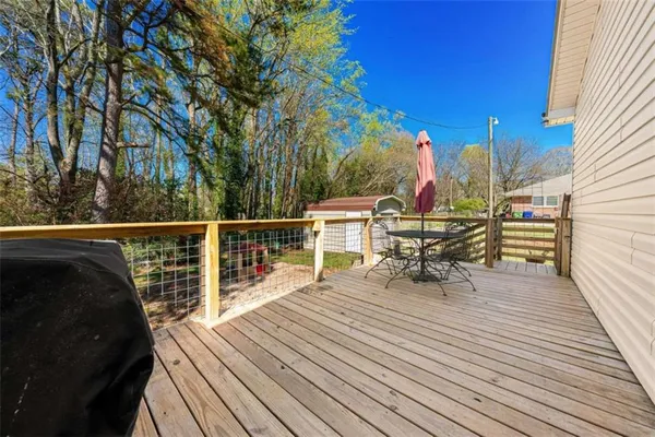 a view of a roof deck with table and chairs a barbeque with wooden floor and fence