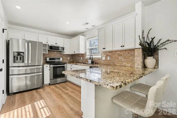 a kitchen with granite countertop white cabinets and stainless steel appliances