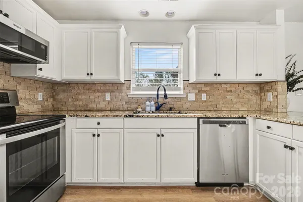 a kitchen with stainless steel appliances granite countertop a stove and a white cabinets