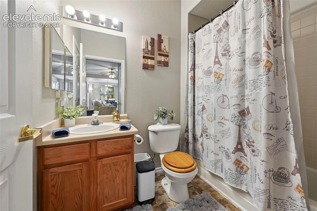 3715 Riviera Grove, Unit 101 Colorado Springs, CO 80922 - Photo 27 of 36 Bathroom featuring a wood-finish vanity with a single basin sink, a large wall mirror, and overhead vanity lighting