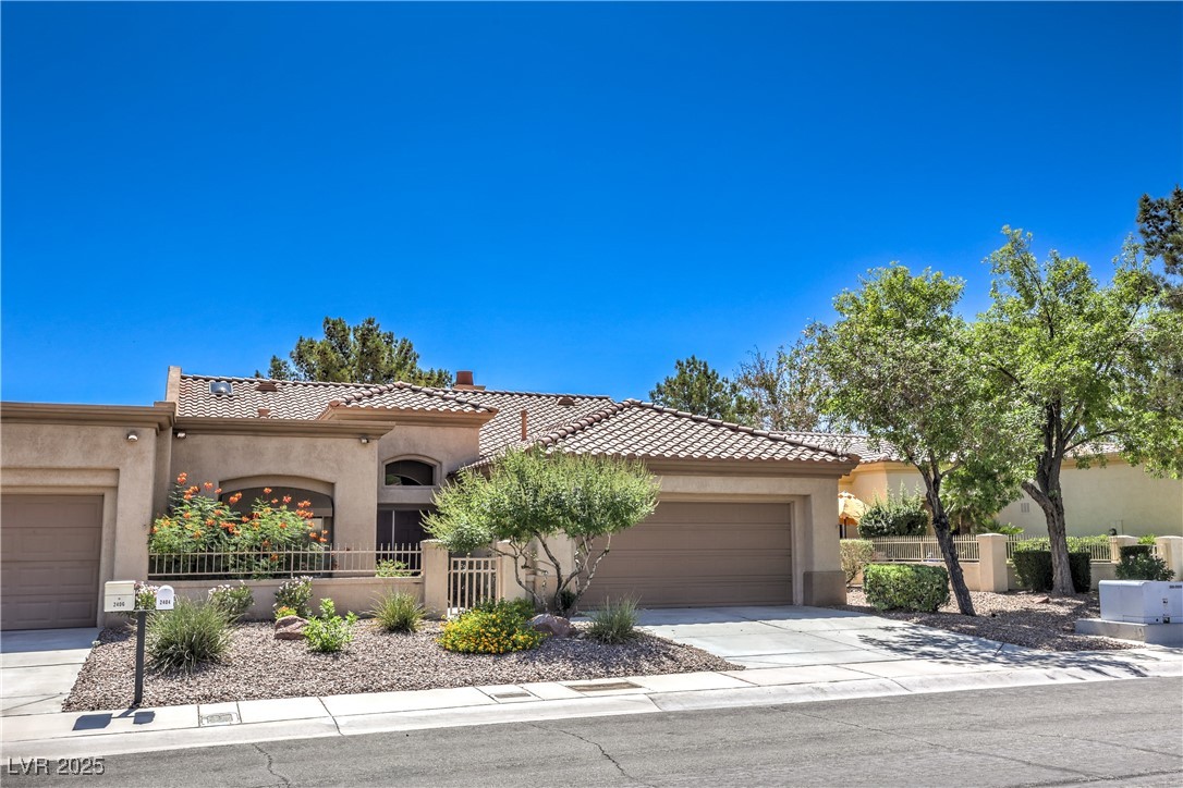 Mediterranean / spanish-style house with a tile roof, a 2 car garage, stucco siding, and driveway