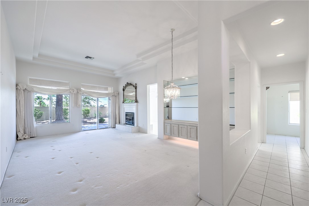2404 Spring Water Drive Las Vegas, NV 89134 - Photo 13 of 27 Unfurnished living room featuring healthy amount of natural light, a chandelier, a glass covered fireplace, recessed lighting, and carpet floors