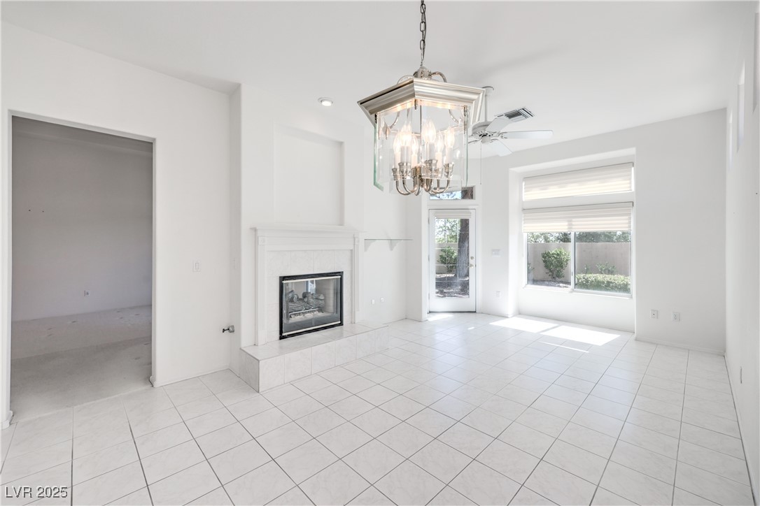 2404 Spring Water Drive Las Vegas, NV 89134 - Photo 15 of 27 Unfurnished living room with light tile patterned floors, a chandelier, and a tiled fireplace