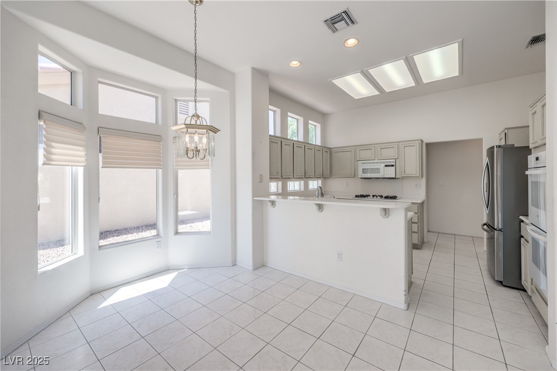 2404 Spring Water Drive Las Vegas, NV 89134 - Photo 5 of 27 Kitchen with white appliances, a chandelier, light countertops, a peninsula, and gray cabinets