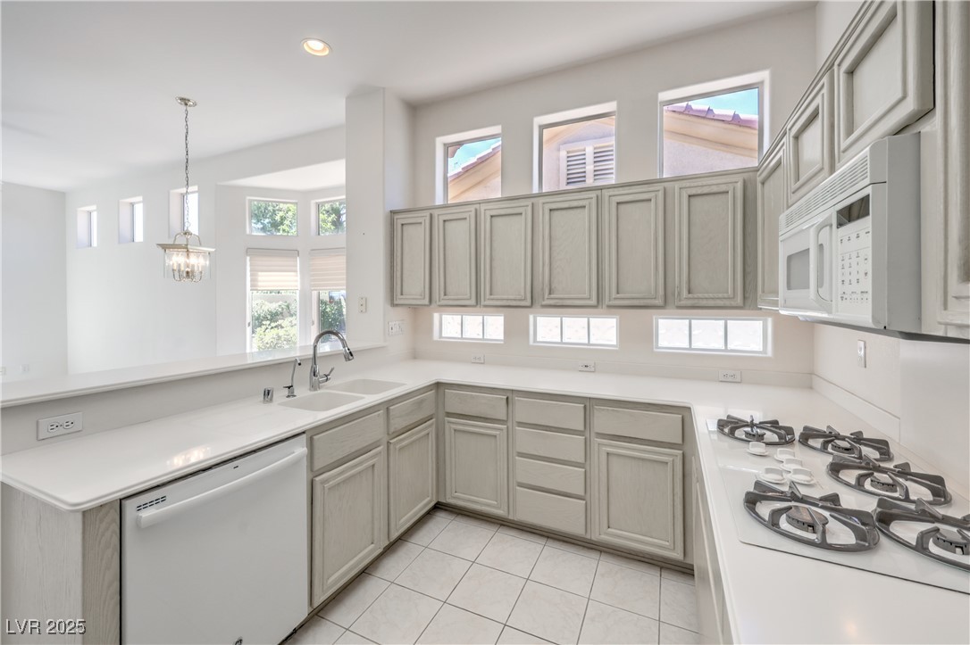 2404 Spring Water Drive Las Vegas, NV 89134 - Photo 7 of 27 Kitchen featuring white appliances, a peninsula, a chandelier, light countertops, and light tile patterned floors