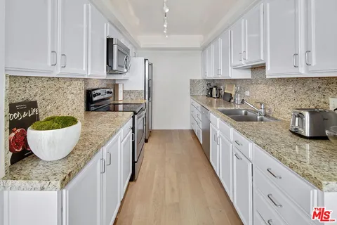 a kitchen with kitchen island granite countertop a sink a stove top oven a counter space and cabinets