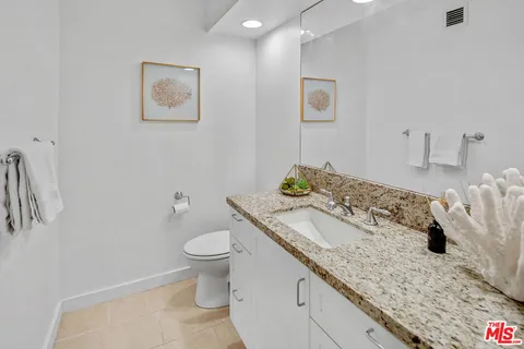 a bathroom with a granite countertop sink and a toilet