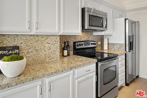 a kitchen with stainless steel appliances granite countertop a sink a stove a microwave and cabinets