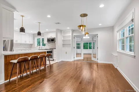 a large kitchen with stainless steel appliances granite countertop a stove a refrigerator a sink a dining table and chairs with wooden floor