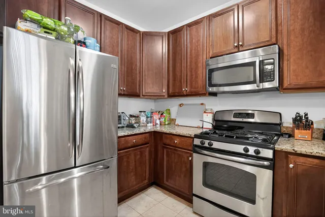 a kitchen with granite countertop a refrigerator and a stove top oven