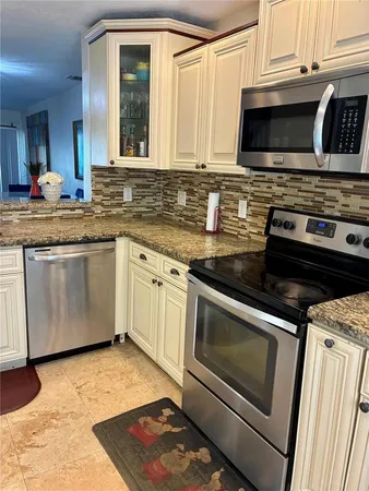 a kitchen with granite countertop a stove top oven microwave and cabinets