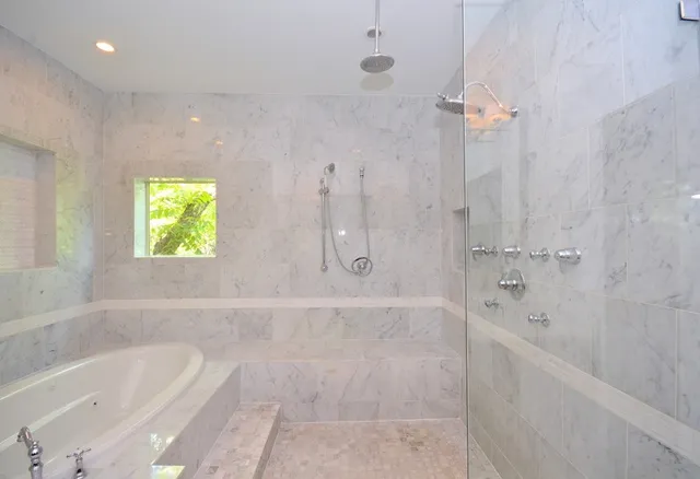 a bathroom with a granite countertop double vanity sink mirror and shower