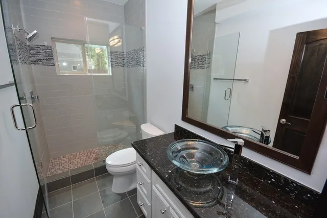 a bathroom with a sink a toilet a mirror and shower