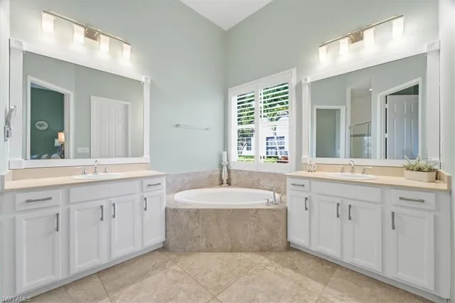 a bathroom with a granite countertop bathtub sink and a window