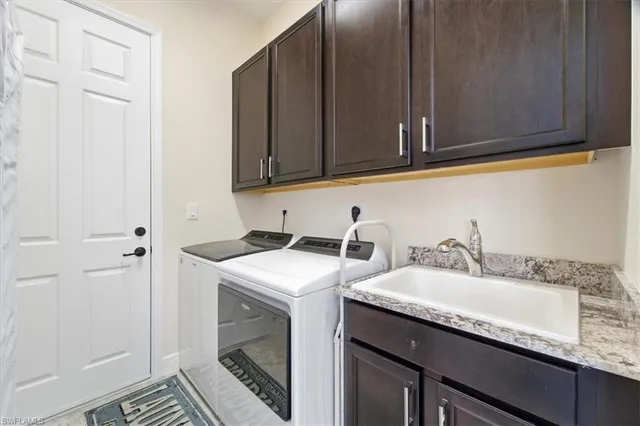 a utility room with stainless steel appliances granite countertop a sink and a cabinets with wooden floor
