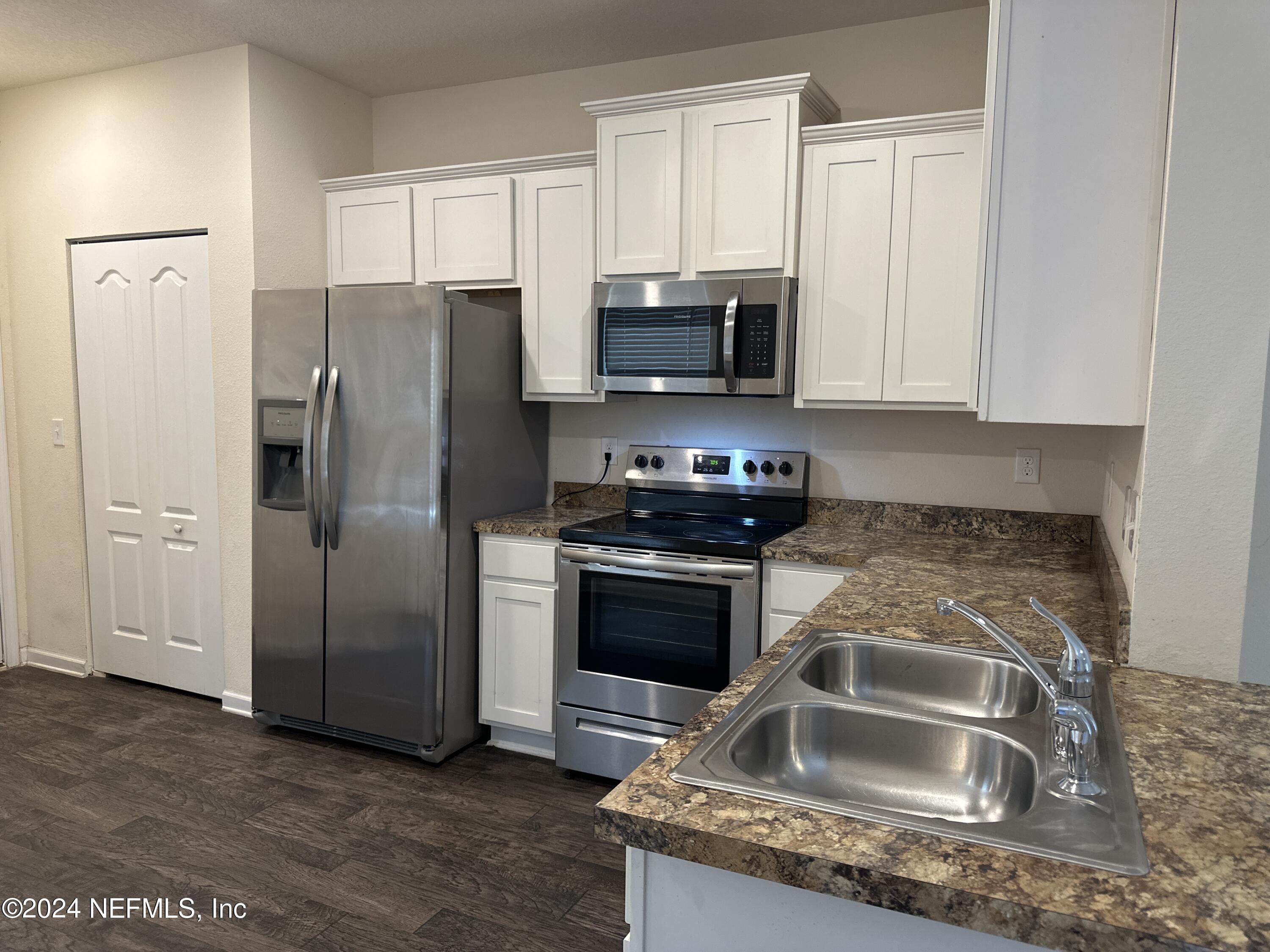 a kitchen with granite countertop a sink and a refrigerator
