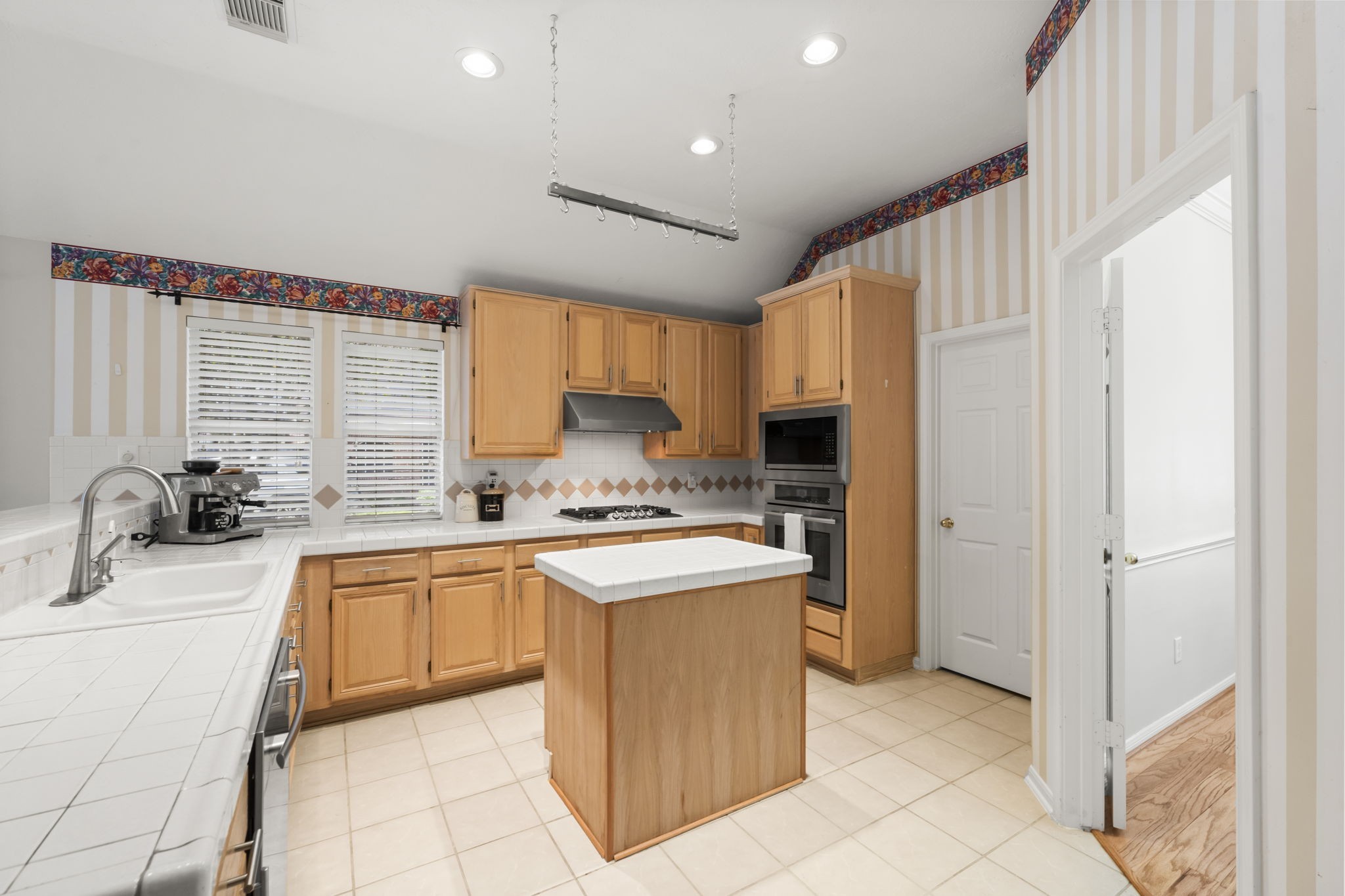 1614 Mercoal Drive Spring, TX 77386 - Photo 19 of 50 The open kitchen features an island and generous countertops, providing abundant space for meal prep, casual dining, and family gatherings while keeping the area open and inviting. The large light and bright laundry room is through the door off the kitchen.