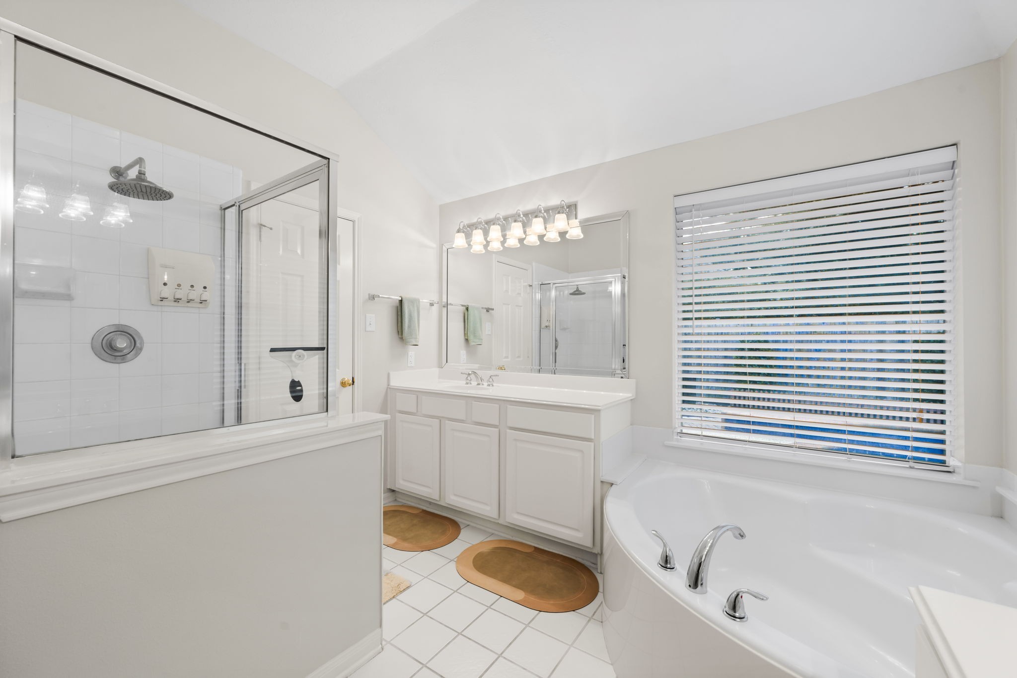 1614 Mercoal Drive Spring, TX 77386 - Photo 26 of 50 This tranquil bathroom features dual vanities, a luxurious soaking tub, and a separate shower with a rainfall showerhead, creating a peaceful space to unwind and refresh.