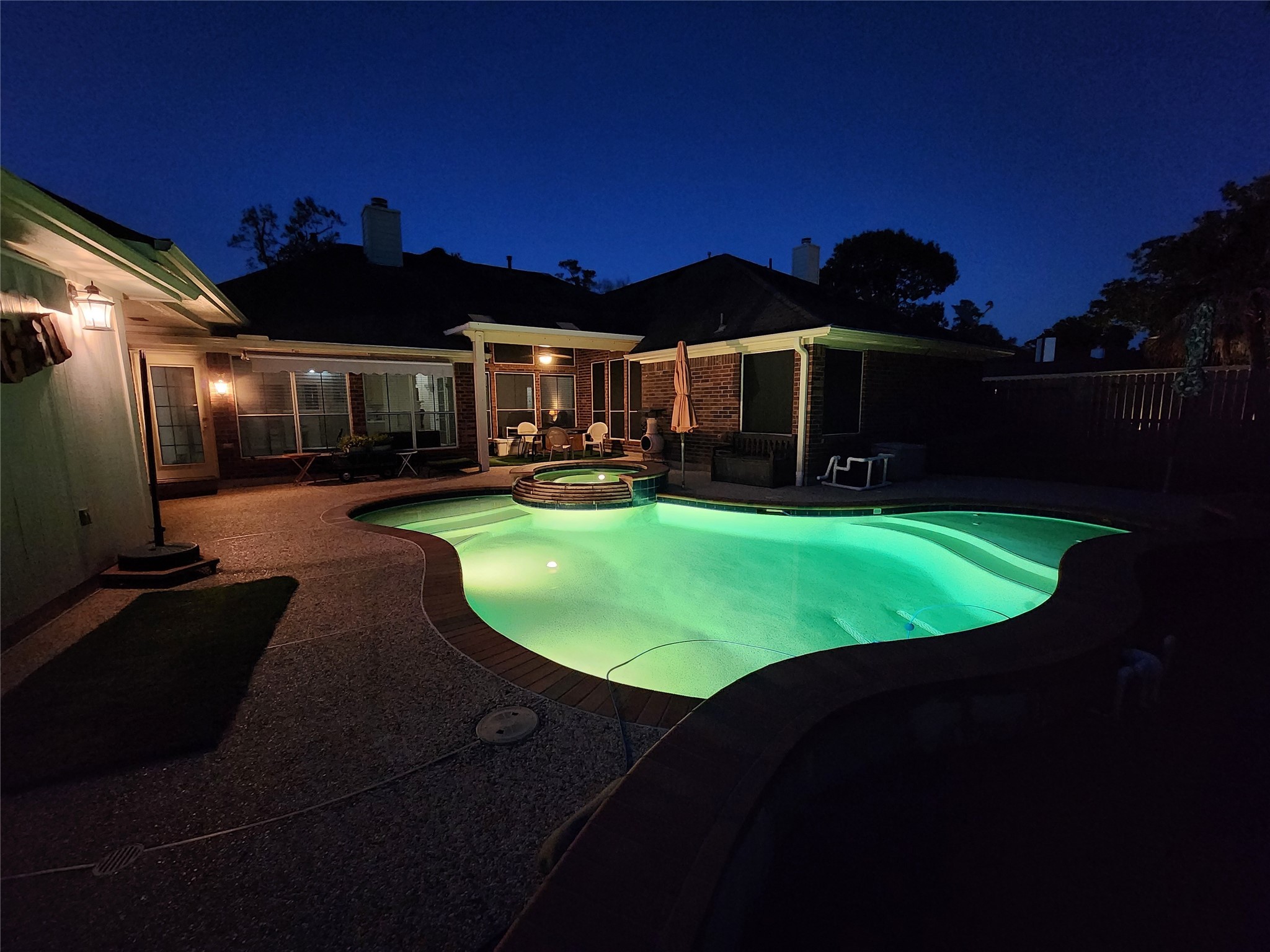 1614 Mercoal Drive Spring, TX 77386 - Photo 4 of 50 In the evening, the backyard transforms into a private retreat as the pool and spa glow with soft lighting, creating a serene setting for relaxing under the stars or hosting unforgettable nighttime gatherings.