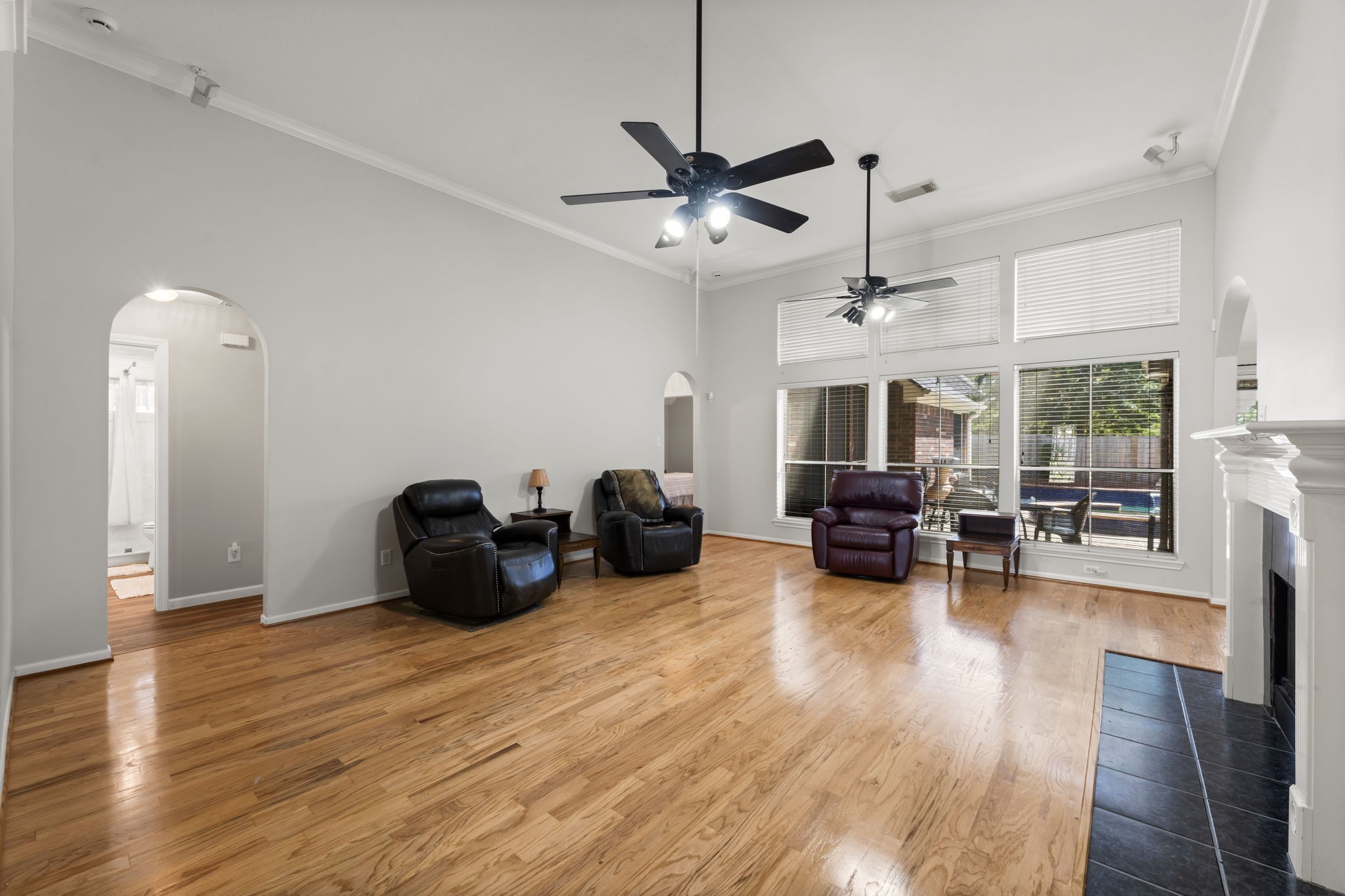 1614 Mercoal Drive Spring, TX 77386 - Photo 10 of 50 A spacious, inviting living area with high ceilings and warm wood floors opens to serene backyard and pool views, ideal for family living and entertaining.