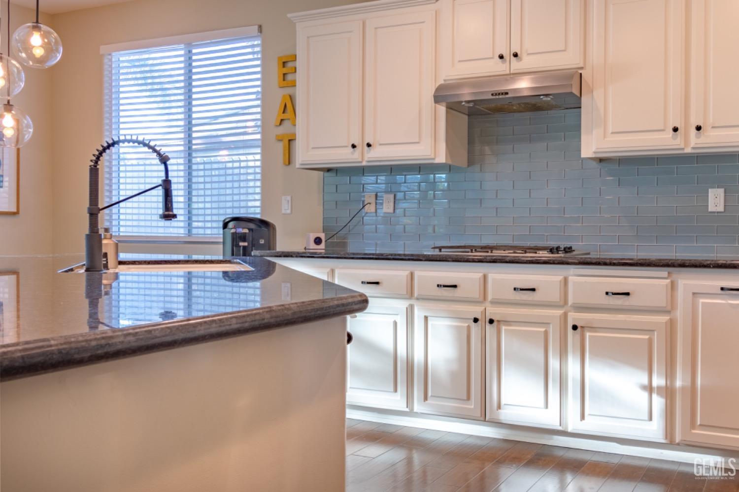 Undisclosed Address Bakersfield, CA 93314 - Photo 11 of 47 a kitchen with granite countertop a sink and white cabinets