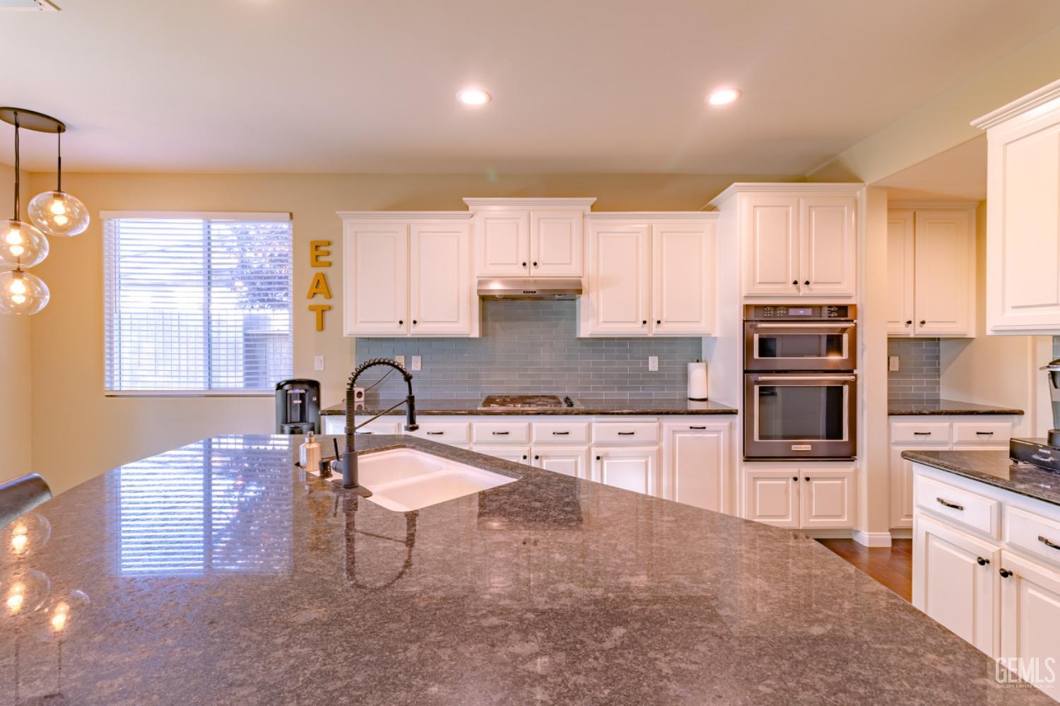 Undisclosed Address Bakersfield, CA 93314 - Photo 10 of 47 a kitchen with kitchen island granite countertop a stove sink and cabinets