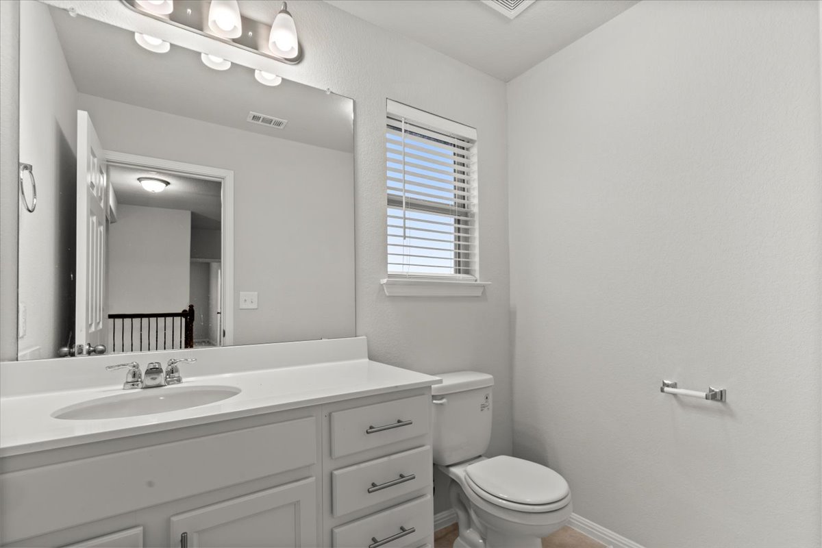 213 Munk Lane Leander, TX 78641 - Photo 23 of 40 a bathroom with a toilet a sink a mirror and vanity