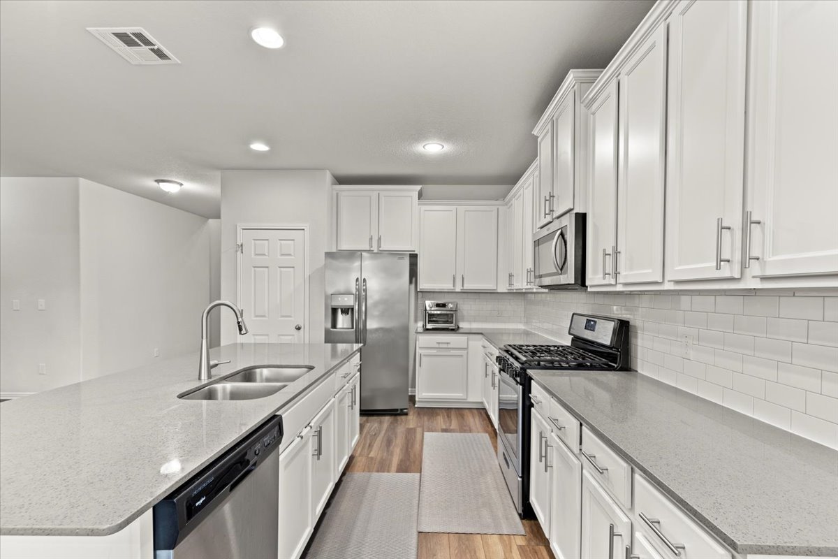 213 Munk Lane Leander, TX 78641 - Photo 8 of 40 a kitchen with stainless steel appliances a sink stove cabinets and refrigerator