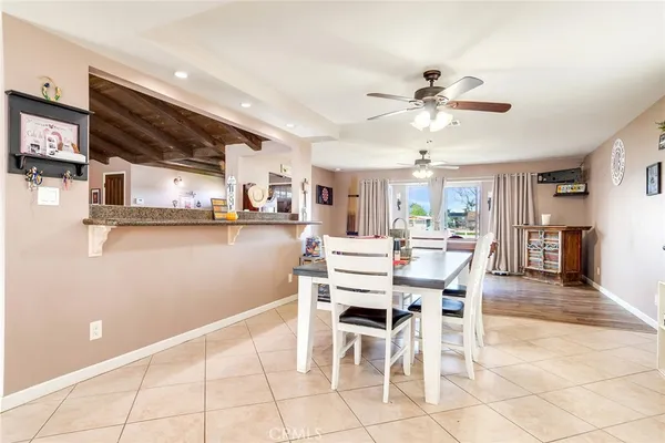 a dining area with stainless steel appliances kitchen island granite countertop a dining table chairs and a refrigerator