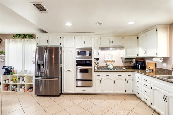 a kitchen with granite countertop a refrigerator and a stove top oven