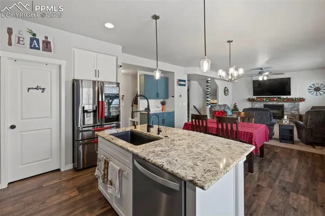 a kitchen with stainless steel appliances granite countertop a sink a refrigerator and a fireplace