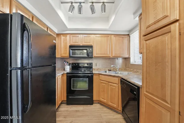 a kitchen with stainless steel appliances granite countertop a refrigerator a stove a sink and a window