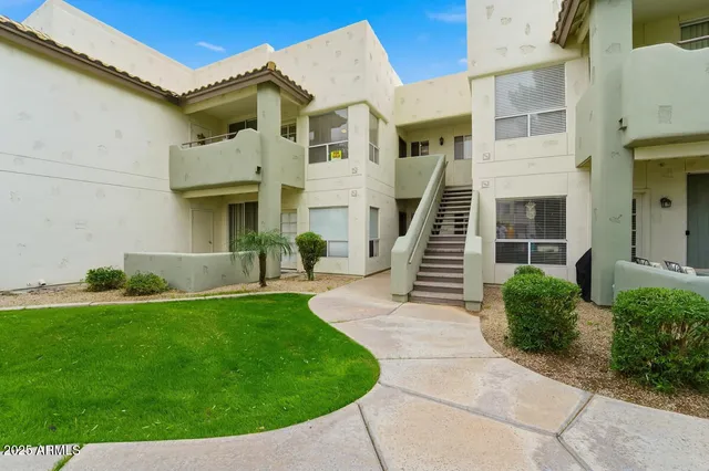 a view of a white house with a small yard and plants
