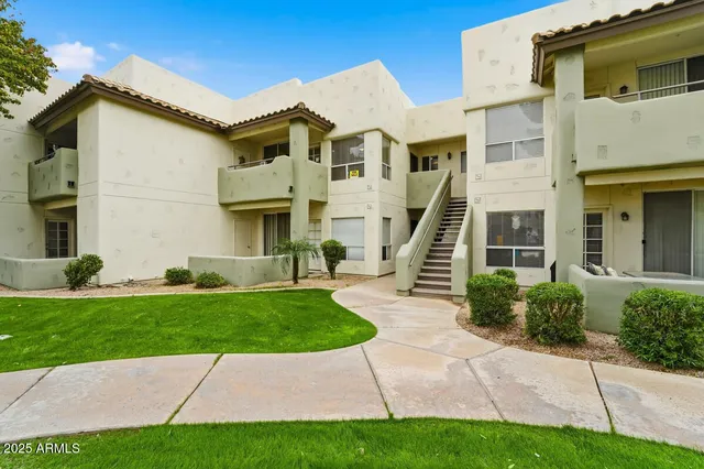 a view of a white house next to a yard with big trees