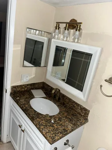 a bathroom with a granite countertop sink and a mirror
