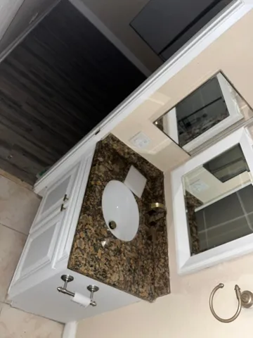 a bathroom with a granite countertop sink and mirror