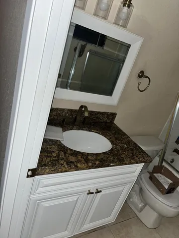 a bathroom with a granite countertop sink and a mirror