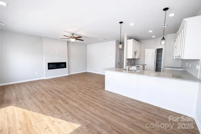 a view of a kitchen with kitchen island a sink wooden floor and a large window