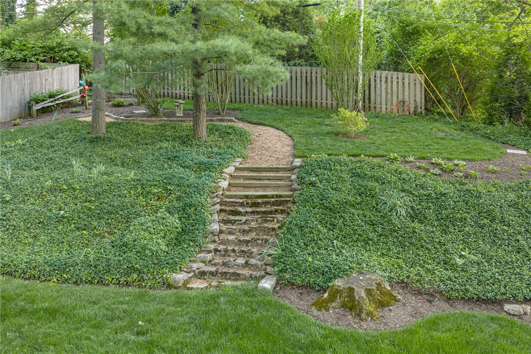 156 West Hadley Road Dayton, OH 45419 - Photo 67 of 71 This serene outdoor space features natural stone steps leading to a fenced yard, surrounded by lush greenery and mature trees.