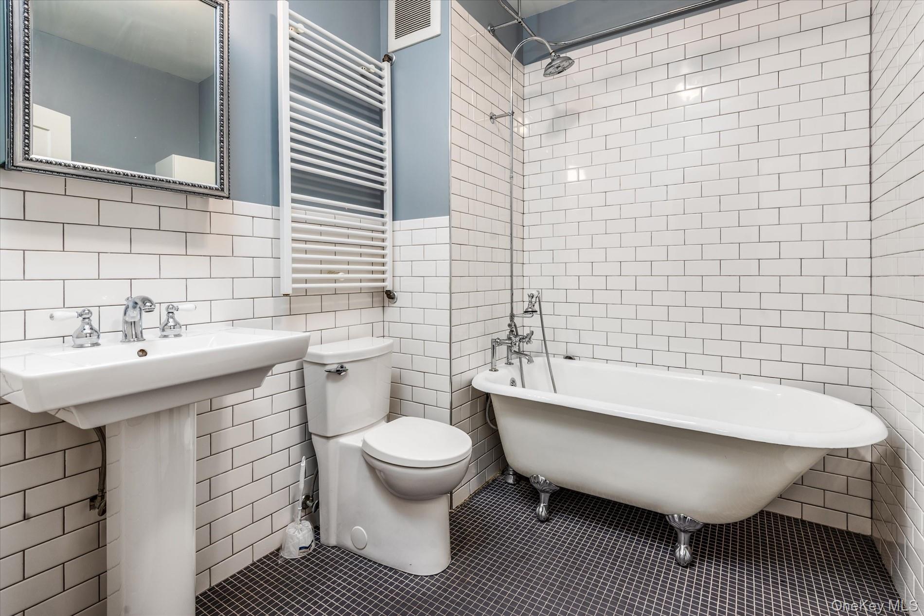 26-19 14th Place Queens, NY 11102 - Photo 13 of 33 Bathroom featuring radiator, tile walls, and a towel warming rack
