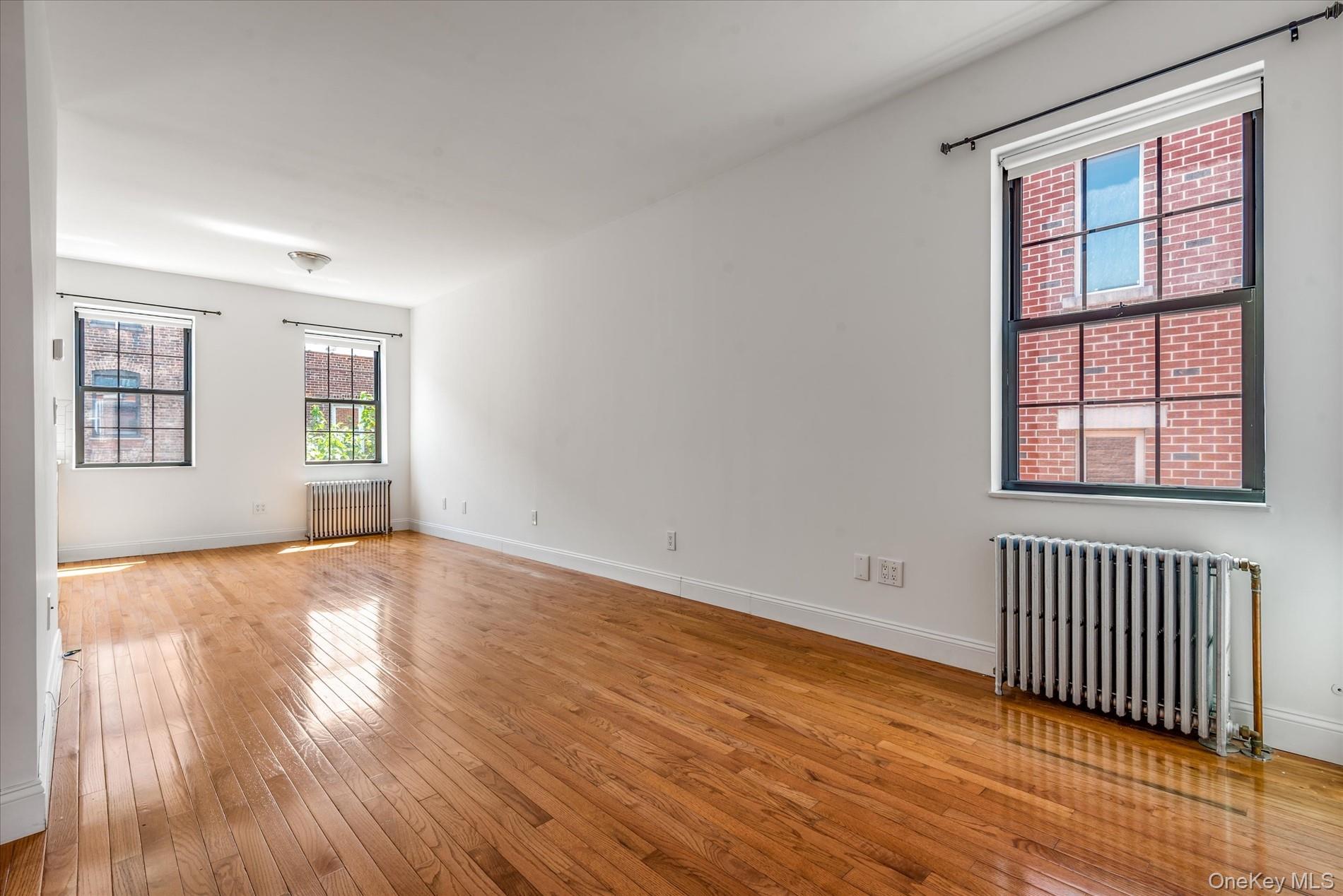 26-19 14th Place Queens, NY 11102 - Photo 19 of 33 Empty room featuring radiator and hardwood / wood-style flooring