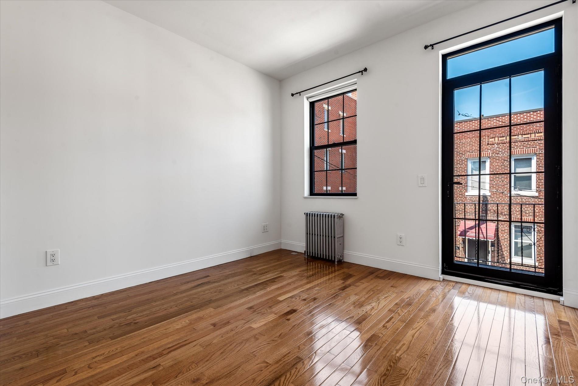 26-19 14th Place Queens, NY 11102 - Photo 25 of 33 Empty room with hardwood / wood-style flooring and radiator