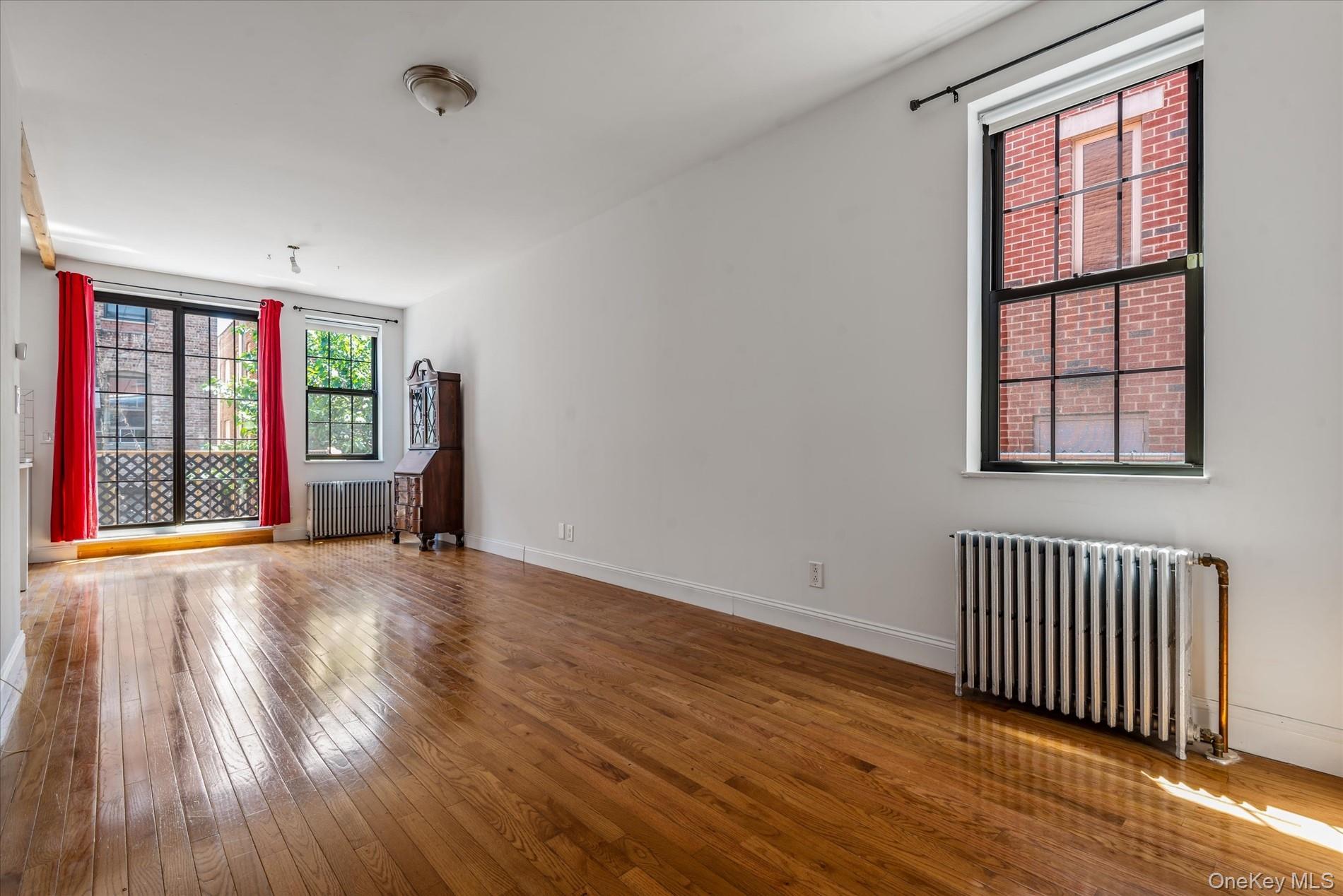 26-19 14th Place Queens, NY 11102 - Photo 3 of 33 Unfurnished room featuring radiator heating unit and hardwood / wood-style floors