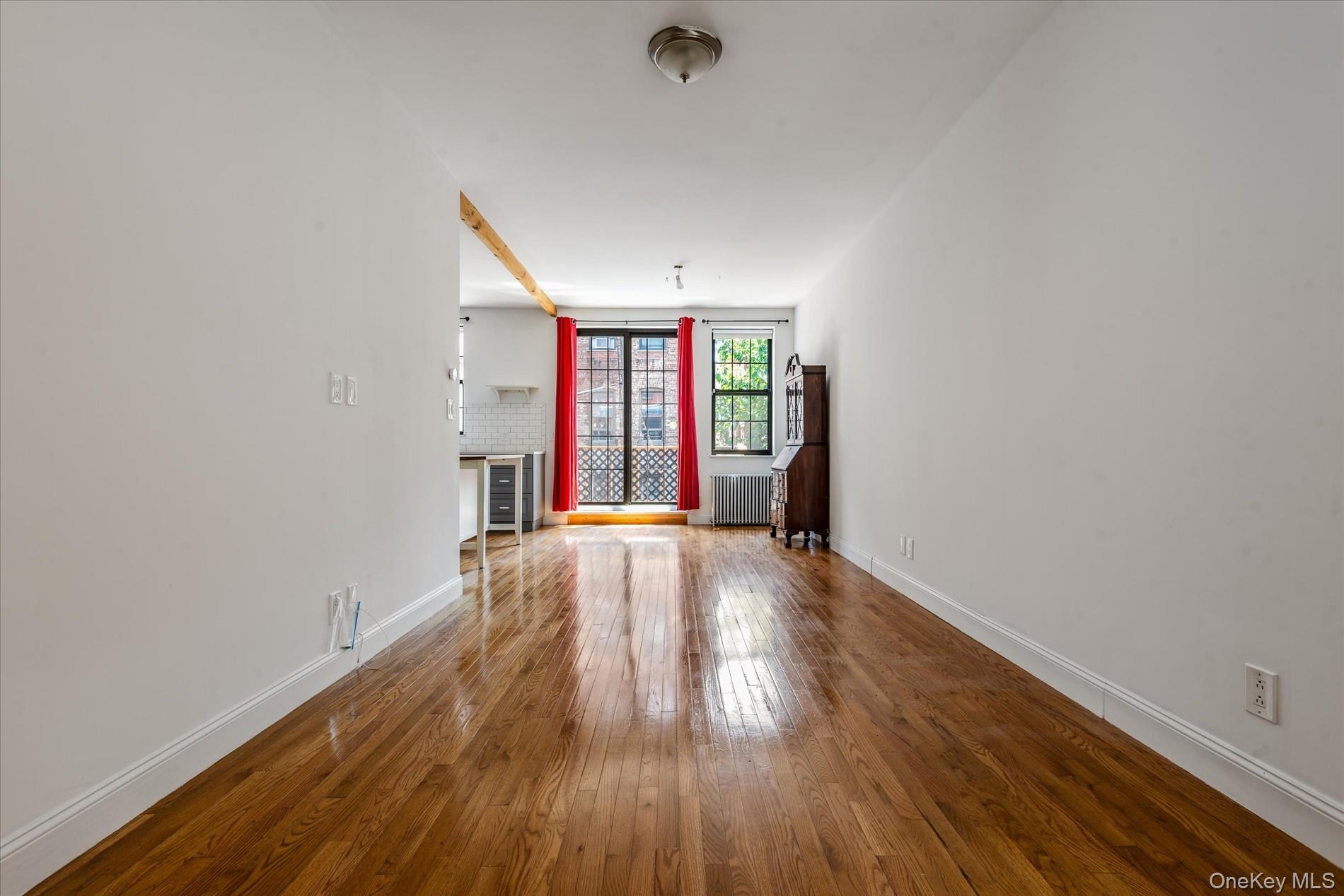26-19 14th Place Queens, NY 11102 - Photo 4 of 33 Unfurnished living room with hardwood / wood-style flooring and radiator heating unit