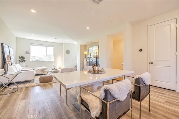 a kitchen with stainless steel appliances granite countertop a sink a stove a refrigerator cabinets and a dining table with wooden floor