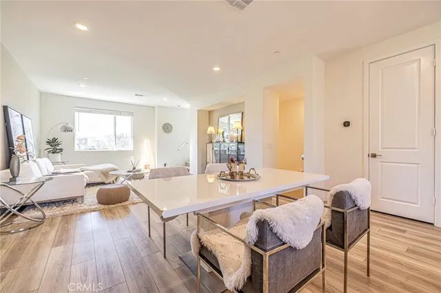 a kitchen with stainless steel appliances granite countertop a sink a stove a refrigerator cabinets and a dining table with wooden floor